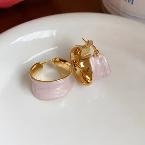 Dettaglio macro di orecchini a cerchio placcati oro 18k con elegante smalto rosa chiaro