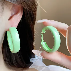 Close-up of green lacquer chunky hoop earrings showing wearing effect and clasp detail.