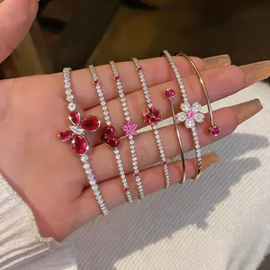 Close-up of elegant luxury bracelets with red crystals and butterfly flower charms