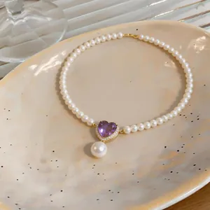 Detailed view of French vintage pearl necklace with purple heart pendant and drop pearl accessory
