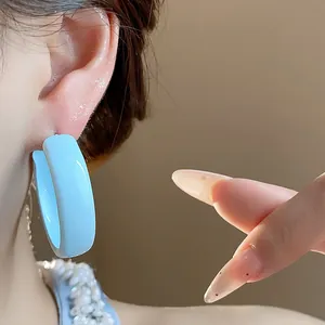 Detailed close-up showing a light blue enamel painted hoop earring on a model's ear