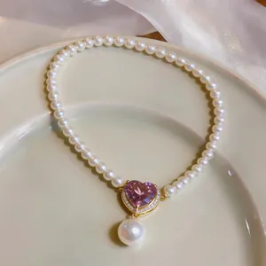 Detailed view of a vintage pearl necklace featuring a pink heart-shaped zircon pendant.