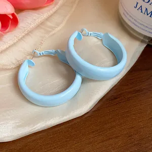 Close-up of sky blue enameled hoop earrings with minimalist circular design