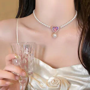 Close-up detail of pearl necklace with pink heart crystal pendant and pearl drop on model