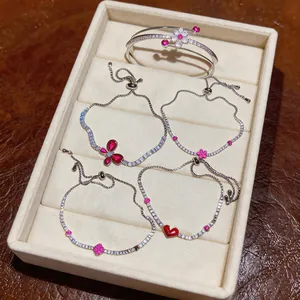 Detailed view of silver-tone bracelets with red zircon butterfly and heart motifs
