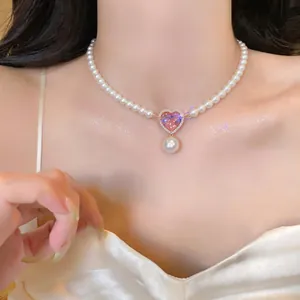 Close-up detail of an elegant pearl necklace featuring a pink heart zircon pendant
