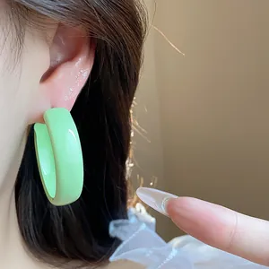 Detailed close-up showing a vibrant green enamel hoop earring with a smooth glossy finish