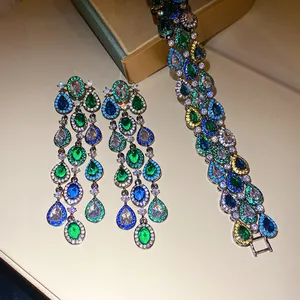 Detailopname van zirkoon kwastjes oorbellen en bijpassende armband met gekleurde stenen.