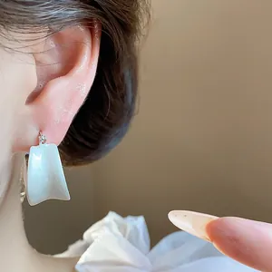Dettaglio orecchini minimalisti in smalto bianco placcati oro 18 carati indossati