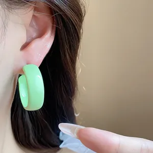 Close-up of a vibrant light green spray-painted hoop earring worn on a person's ear