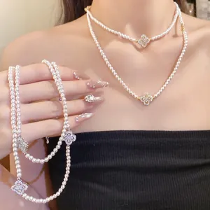 Elegant multi-strand pearl choker necklace with zircon clover charms on an Asian model