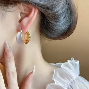 Elegante primo piano di orecchini a cerchio in smalto placcato oro 18 carati indossati da una modella