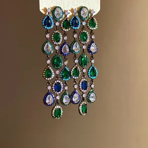 Close-up van elegante kwastjesoorbellen met groene, blauwe en heldere zirkoonstenen
