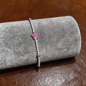 Macro detail of an elegant pink flower zircon bracelet displayed on grey velvet roll