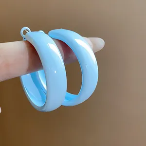 Close-up view showing the glossy light blue enamel finish on round hoop earrings.