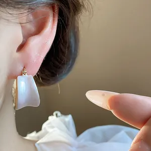 Primo piano di orecchini minimalisti placcati in oro 18k con smalto a goccia