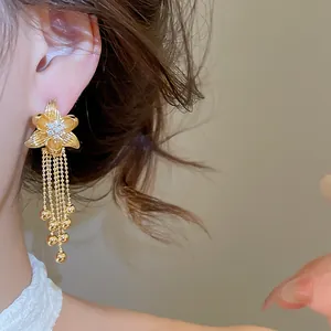Dettaglio ravvicinato di orecchini placcati oro 18k con fiore di zirconi e nappe.