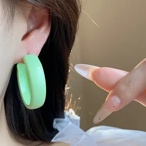 Detailed close-up view of vibrant mint green spray-painted chunky hoop earrings worn on ear