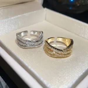 Détail des bagues croisées en X dorées et argentées serties de pavés brillants