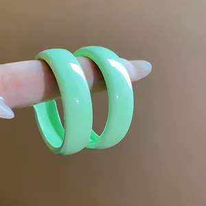 Macro detail showing the glossy finish of mint green spray-painted hoop earrings.