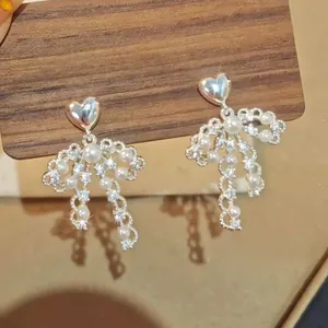 Close-up of French vintage heart pearl bow earrings with sparkling crystals