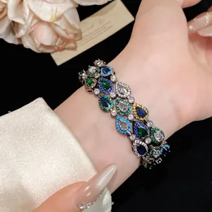 Close-up van een luxe gelaagde armband met kleurrijke peervormige zirkonia op de pols