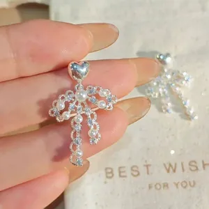 Close-up detail of French style heart pearl bow earrings with sparkling crystals