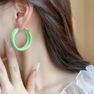 Close-up of elegant mint green matte spray-painted hoop earrings worn on ear.