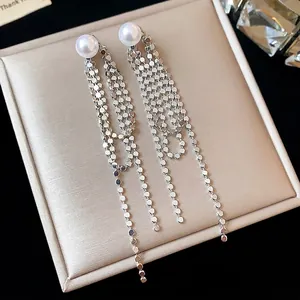 Eleganti orecchini pendenti in argento con perle presentati su una scatola di lusso