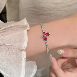 Detailed view of an elegant silver bracelet with red zircon butterfly charm on a female wrist
