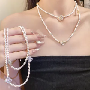Detail of elegant pearl necklace with zircon-studded four-leaf clover pendant on model