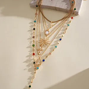 Detail of a vintage layered necklace set with gold chains, colorful beads and a sun pendant.