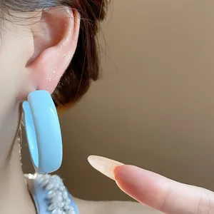 Close-up of a sky blue painted hoop earring worn by a model in a minimalist style.