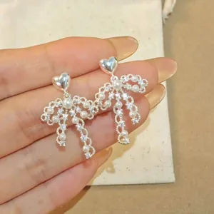 Close-up detail of vintage heart pearl bow earrings with rhinestone embellishments