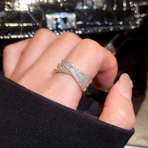Vue macro détaillée d'une bague dorée en forme de X ornée de pierres de cristal pavées
