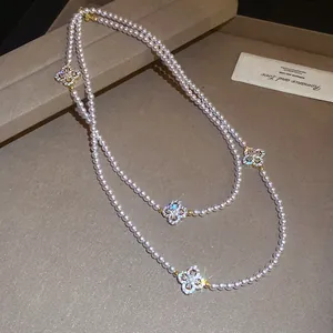Close-up detail of an elegant pearl necklace featuring sparkling CZ inlaid clover pendants