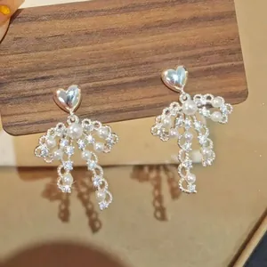 Elegant heart-shaped stud earrings with pearl and crystal bow-knot tassel details.