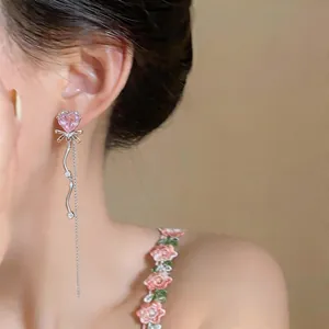 Détail d'une boucle d'oreille cœur rose élégante avec nœud et longue frange argentée