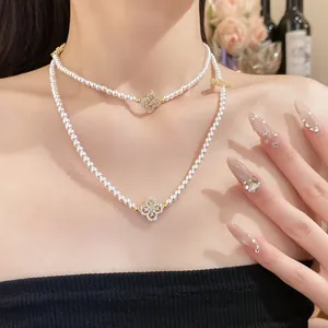 Detail view of double-layer pearl necklace with sparkling zircon clover charms