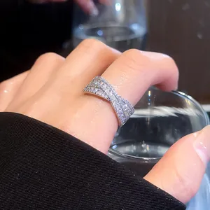 Vue rapprochée d'une bague croisée en argent avec pierres étincelantes au doigt.