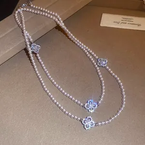 Detailed view of elegant pearl necklace with sparkling zircon clover charms.