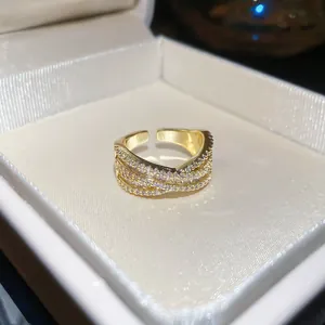 Gros plan détaillé d'une bague ajustable élégante en forme de X dorée avec pierres pavées