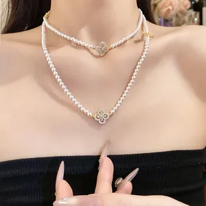 Close-up of a layered pearl necklace with an elegant zircon flower pendant on a model