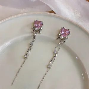 Vue rapprochée de boucles d'oreilles élégantes en cristal rose avec nœud et longs pompons