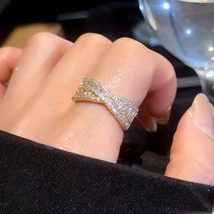 Gros plan d'une bague croisée en X dorée avec des cristaux étincelants et une finition de luxe.