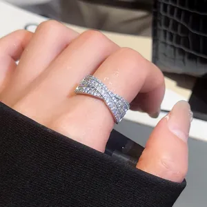 Gros plan d'une bague en X argentée ornée de pierres scintillantes sur une main.