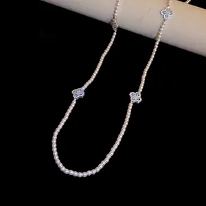 Macro view of an elegant pearl bead necklace featuring sparkling zircon flower charms.