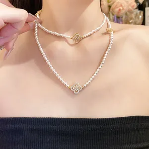 Close-up of elegant layered pearl necklace with zircon flower pendant worn by a model.