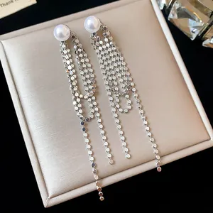 Primo piano di eleganti orecchini a nappa in argento con perle e dischi metallici.