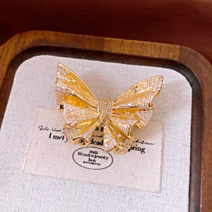 Close-up of golden butterfly brooch with shimmering crystals in a wooden jewelry box